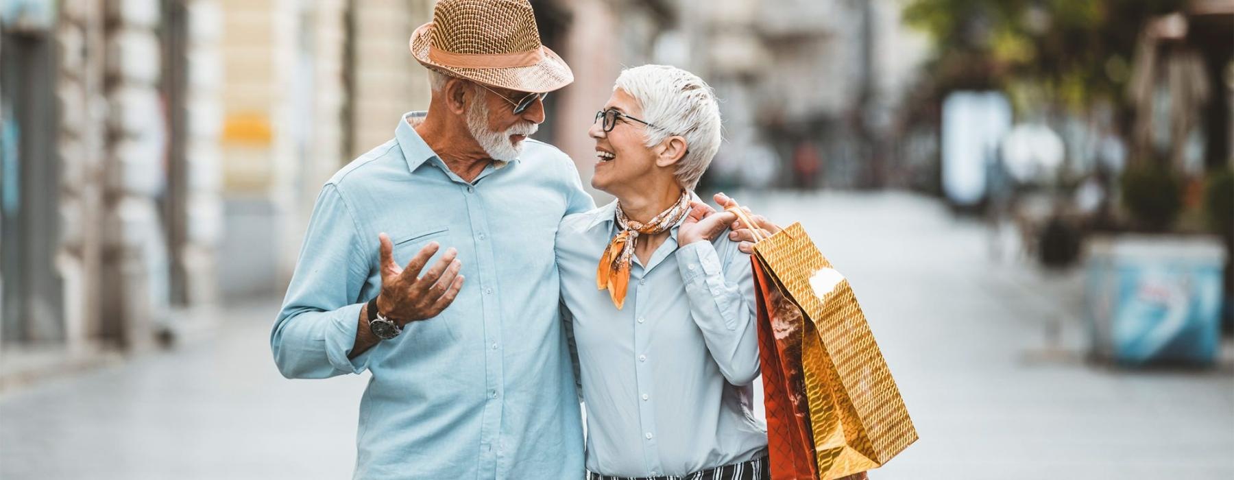 a man and woman holding shopping bags while walking