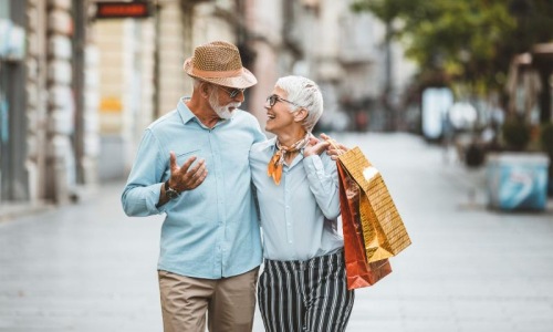 a man and woman holding shopping bags while walking